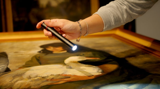 Goose Girl painting being examined